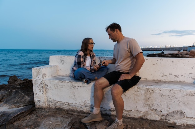 Papá toma el teléfono de la hija de un adolescente durante un paseo nocturno por el mar