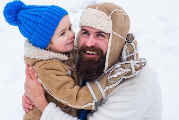 Papa und Junge lächeln und umarmen glücklicher Familiensohn umarmt seinen Vater im Winterurlaub