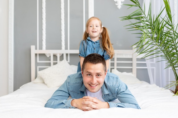 Papa und kleine Tochter haben viel Spaß beim Spielen und Kuscheln zu Hause auf dem Bett