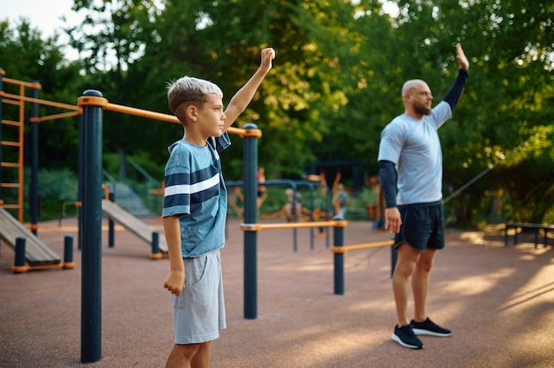 Papa und Sohn, Sporttraining auf Spielplatz im Freien. Die Familie führt einen gesunden Lebensstil, Fitnesstraining im Sommerpark