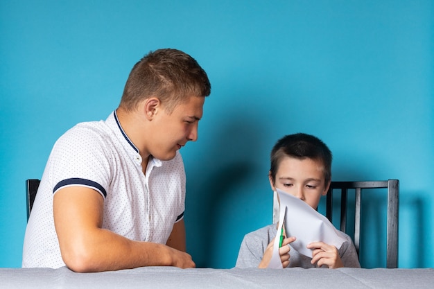 Papa unterrichtet das Kind zu Hause, Homeschooling. Vater hilft seinem Sohn bei den Hausaufgaben, Scherenschnitt