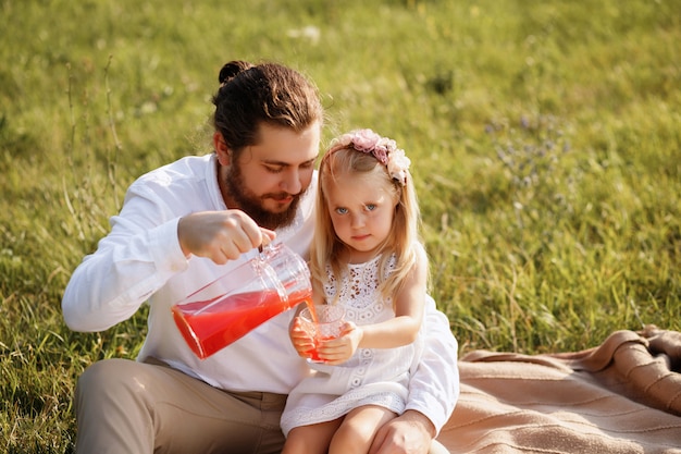papá vierte jugo a hija picnic de verano