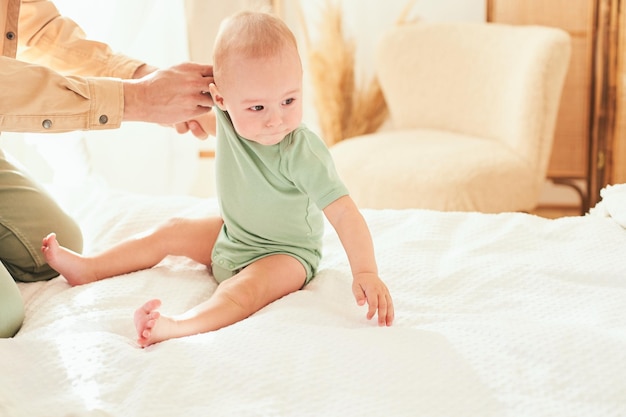 Foto papa wechselt die kleidung seines kleinen sohnes, der auf dem bett sitzt