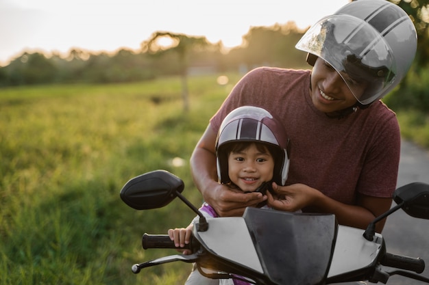 Papai ajuda a filha a prender o capacete