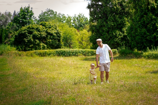 Papai caminha com sua filhinha na clareira, horário de verão