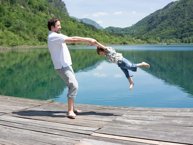 Papai e filho jogando no lago da montanha