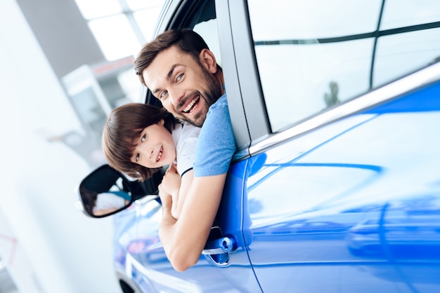 Papai e filho olham pela janela de um carro recém-comprado.