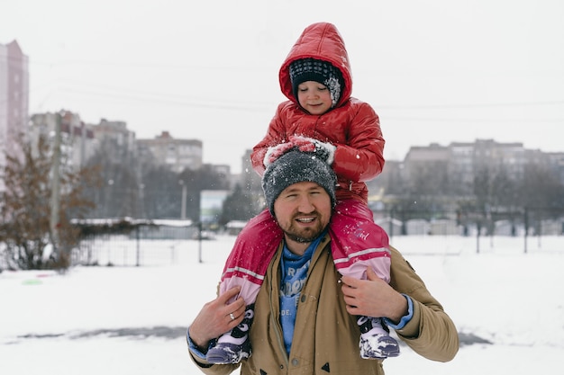 Foto papai está segurando uma filha nos ombros.