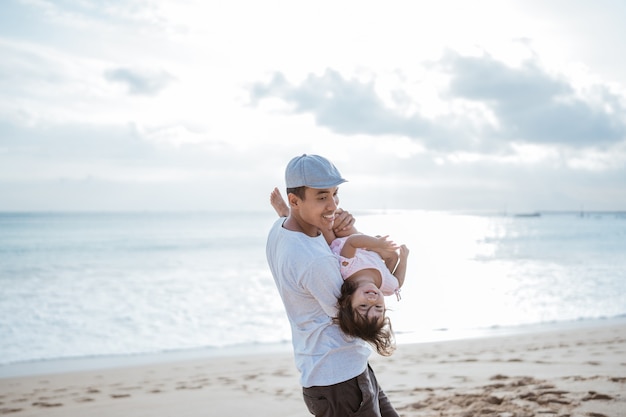 Papai gosta de brincar com a filha na praia se divertindo juntos