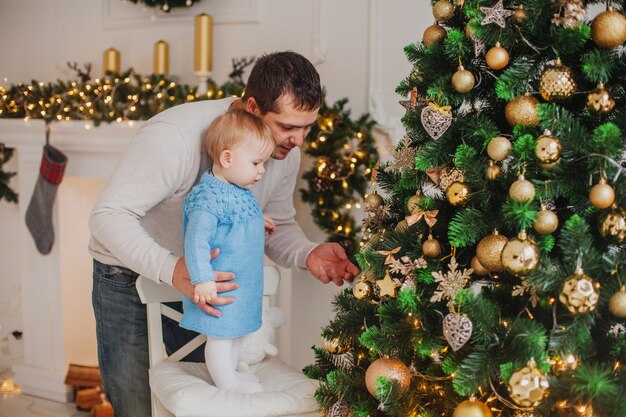 Papai mostra os brinquedos da filha na árvore de natal