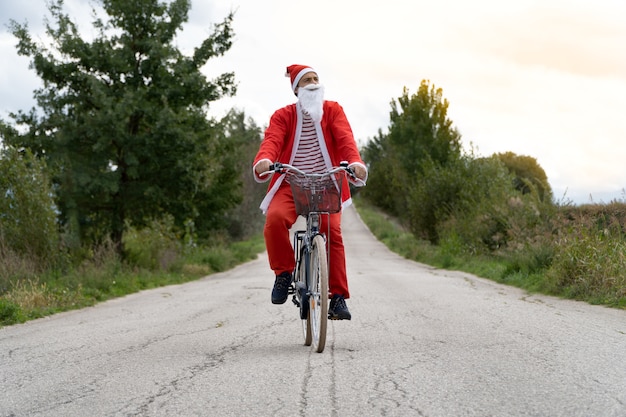 Papai Noel andando de bicicleta na rua.