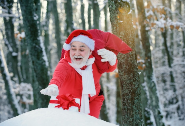 Papai Noel caminhando para a floresta de inverno com um saco de presentes neve paisagem feliz ano novo