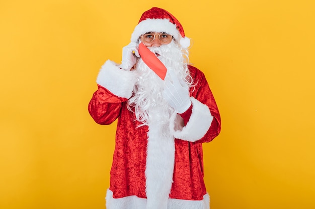 Papai Noel colocando uma máscara facial vermelha, amarela