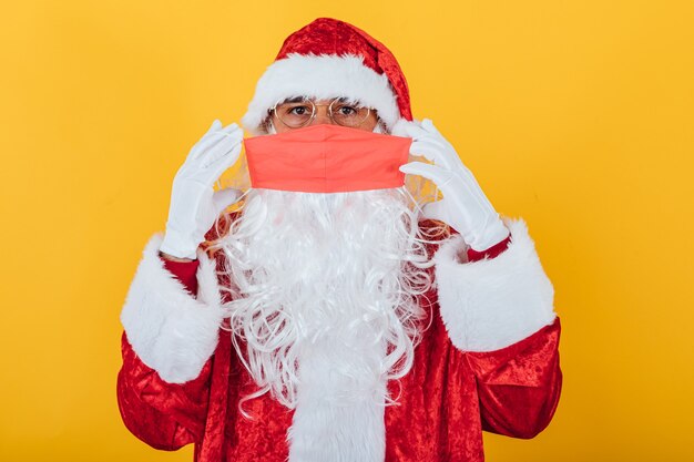 Papai Noel colocando uma máscara facial vermelha, amarela