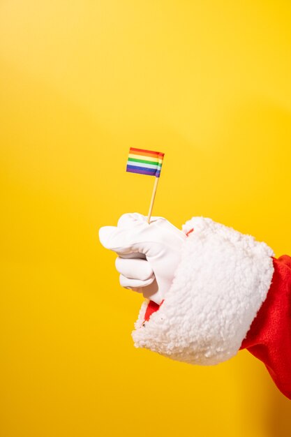 Papai Noel com as mãos segurando uma mini bandeira gay