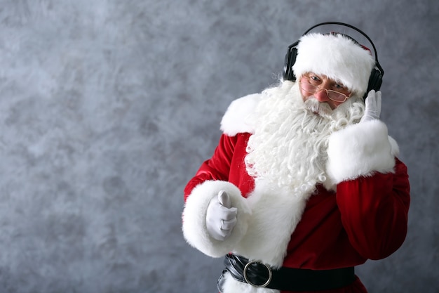 Papai Noel com fones de ouvido ouvindo música no fundo cinza da parede