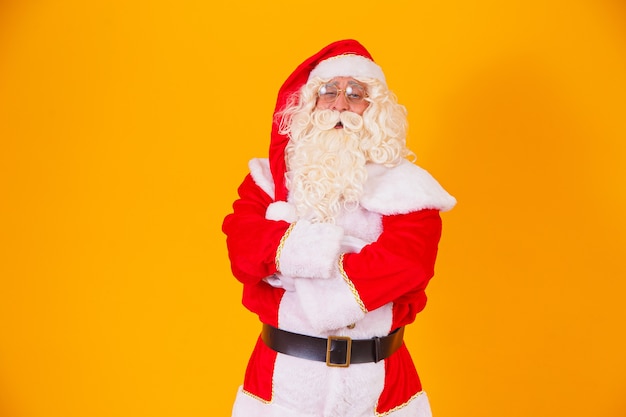 Papai Noel com os braços cruzados em fundo amarelo.