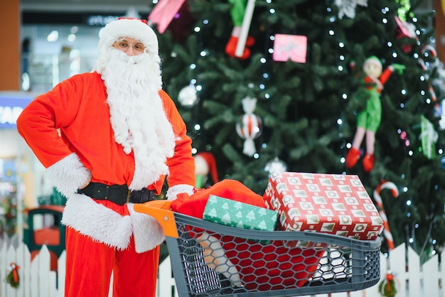 Papai Noel com presentes no shopping no fundo da árvore de Natal