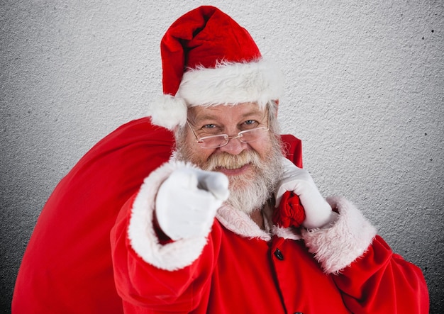 Foto papai noel com saco de presentes apontando para a câmera