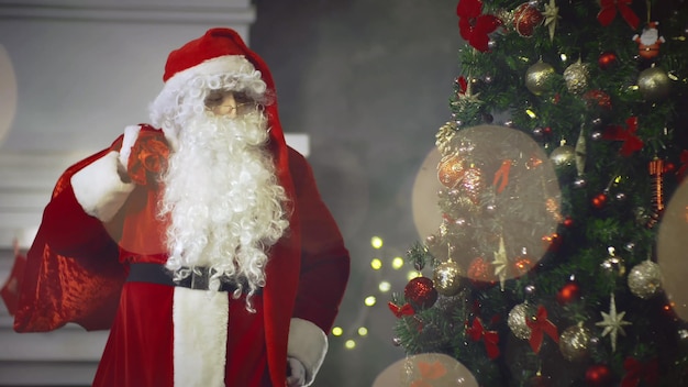 Papai noel com saco de presentes na árvore de natal de fundo na véspera de ano novo