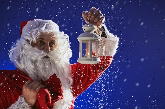 Papai Noel com uma longa barba branca segura castiçal com vela acesa
