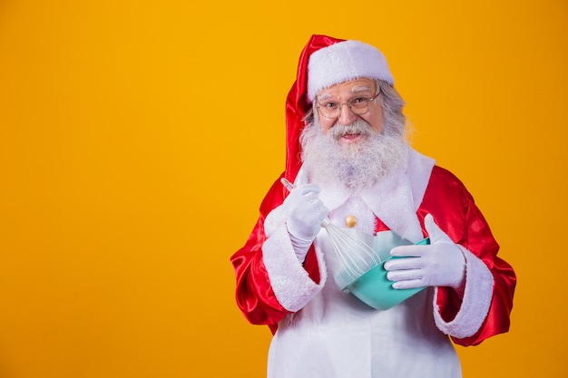 Papai noel com uma tigela batendo bolo em fundo amarelo