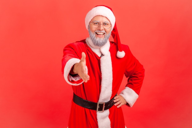 Papai Noel dando a mão para um aperto de mão, dando as boas-vindas às pessoas para a festa de Natal.