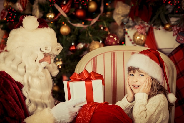 Papai Noel e criança em casa. Presente de Natal. Conceito de férias em família