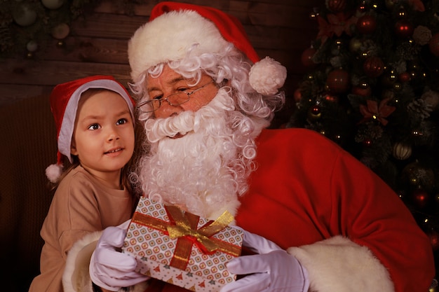 Papai Noel e criança em casa. Presente de Natal. Conceito de férias em família.