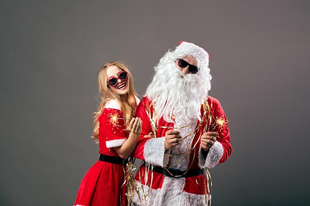 Papai Noel e jovem linda sra. Noel em óculos de sol estão segurando estrelinhas nas mãos