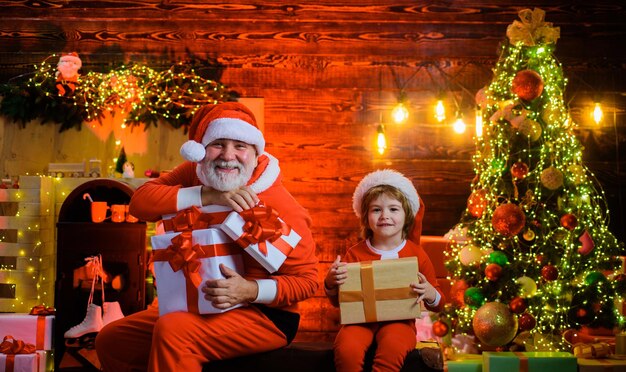 Foto papai noel e menino com presentes de natal no quarto decorado para o natal feliz papai noel homem e