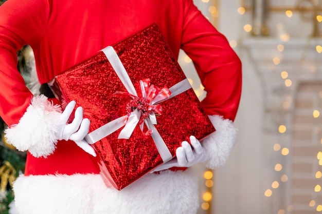 Papai Noel está segurando um presente em um pacote vermelho nas costas