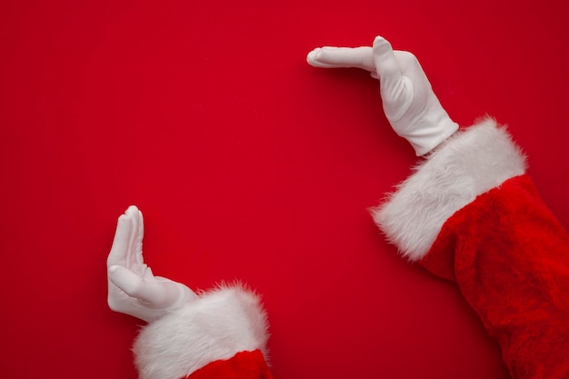 Papai noel fazendo moldura com a mão no fundo vermelho com espaço de cópia