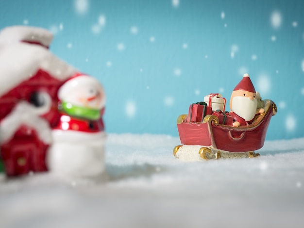 Papai Noel feliz com a caixa de presentes no trenó da neve que vai nevar casa.