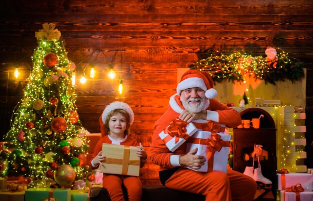 Papai Noel homem e menino papai noel em casa presente de natal conceito de férias em família sorrindo pouco