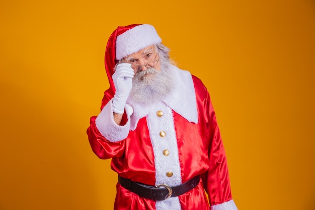 Papai Noel olhando para a câmera. O Natal está chegando. Feliz Natal. Papai Noel está assistindo. Segurando seus óculos.