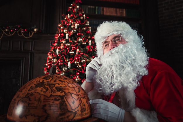 Papai noel, olhando para o globo da terra