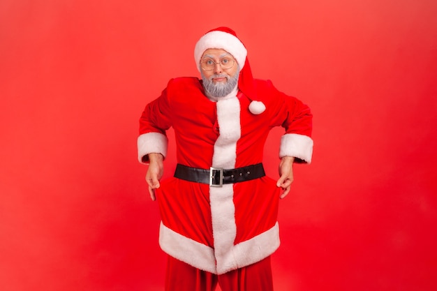 Foto papai noel revelando bolsos vazios, gesticulando que não tenho dinheiro antes das férias de natal.