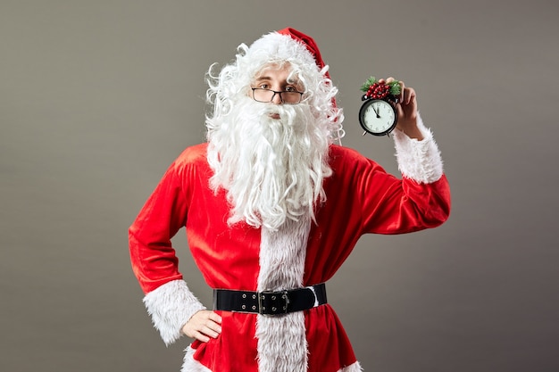 Papai Noel segura um relógio que mostra cinco às doze