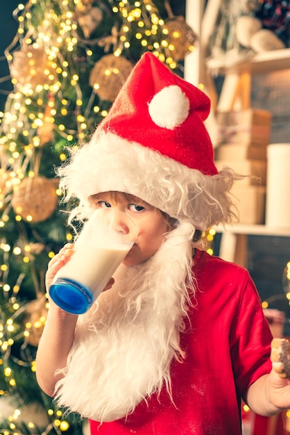 Papai Noel segurando biscoitos de Natal e leite contra fundo de árvore de Natal, garoto de feliz ano novo ...