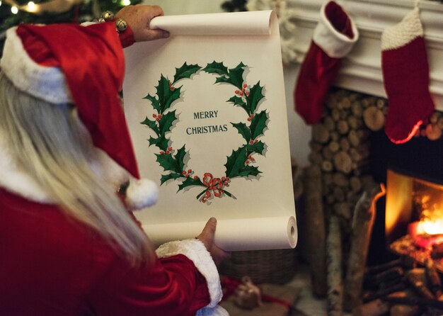 Papai Noel segurando o rolo de papel de feliz Natal