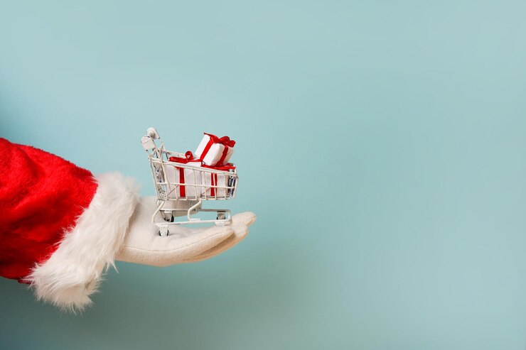 Foto papai noel segurando um carrinho de compras com caixas de presentes na mão fundo azul com espaço de cópia