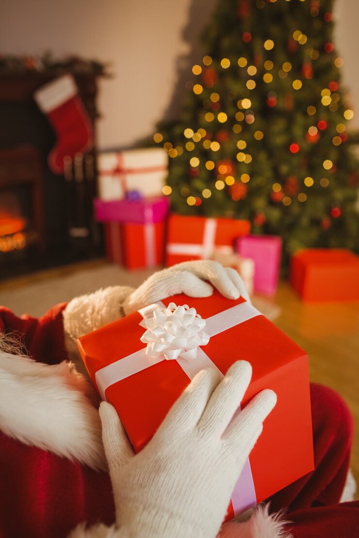 Foto papai noel segurando um presente vermelho com um arco branco