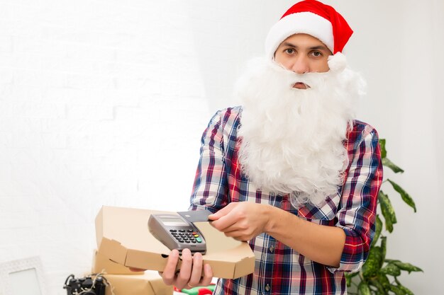 Papai Noel segurando uma caixa de pizza e um terminal pos no fundo branco