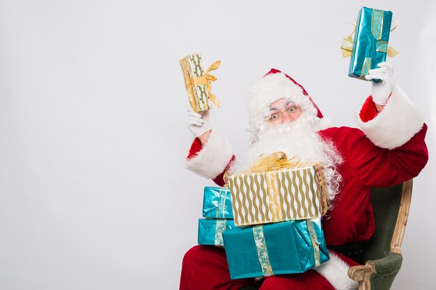 Foto papai noel segurando uma pilha de caixas de presentes isoladas