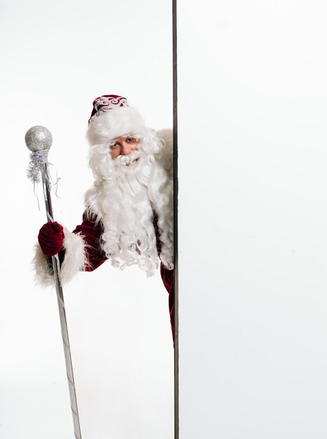 Papai Noel segurando uma placa em branco Engraçado Papai Noel espreitando atrás de uma placa de publicidade vazia Outdoor de Natal