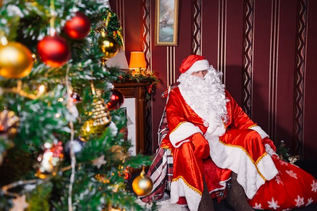 Papai Noel sentado ao lado de uma árvore de Natal