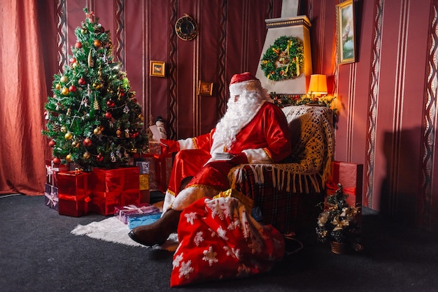 Papai Noel sentado ao lado de uma árvore de Natal