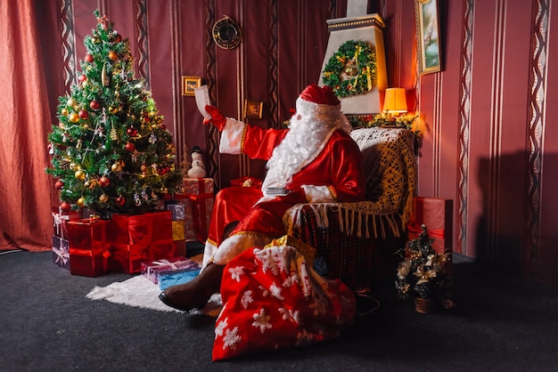 Papai Noel sentado ao lado de uma árvore de Natal