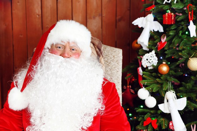 Papai noel sentado em uma cadeira de balanço confortável perto do natal em casa